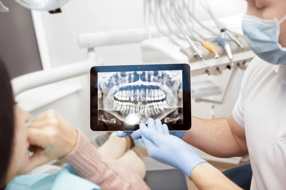 Lekarz dentysta analizujący zdjęcie RTG zębów na tablecie – 40 lat doświadczenia gabinetu stomatologicznego Dental-Wit w Będzinie.